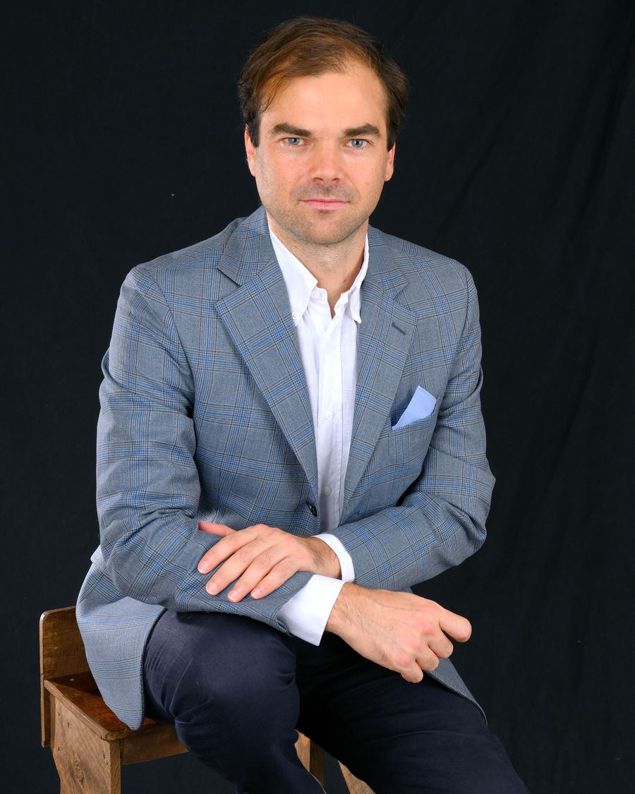 Guillaume Antier, assis sur un tabouret en bois